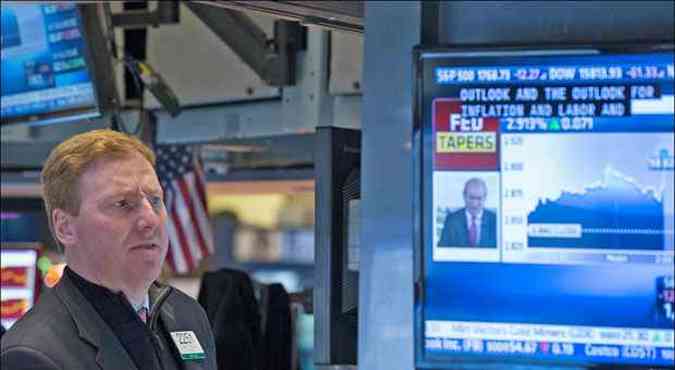 Operador acompanha anncio da deciso do Fed pela TV, ontem, durante o prego da Bolsa de Valores de Nova York(foto: Lucas Jackson/Reuters)