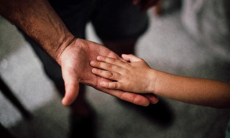 Criança argentina recebe tripla filiação com dupla paternidade(foto: Juan Pablo Serrano Arenas/Pexels) A imagem mostra duas mãos suspensas. Uma mão de criança pousa sobre uma mão adulta.
