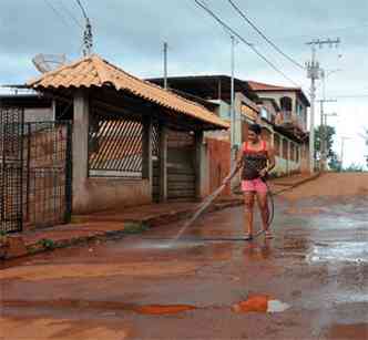 Eva Eugenia Goncalves, 54, limpa a rua em frente sua casa, devido ao p acumulado pelas atividades de mineradoras e o trfego intenso de caminhes carregados de minrio(foto: Tulio Santos/EM/D.A Press)