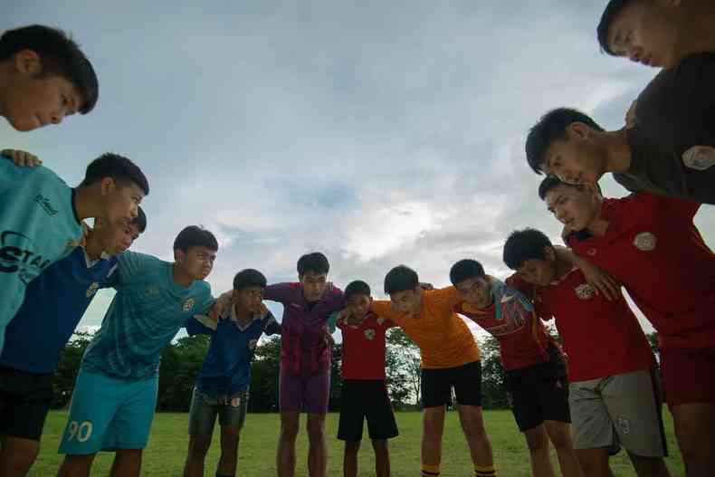 Meninos de time de futebol esto abraados, em roda, tendo ao fundo o cu