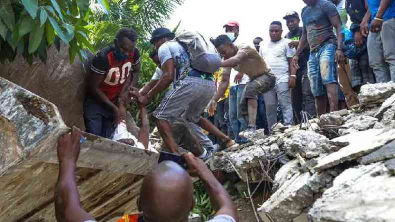 Homens tentam resgatar um sobrevivente debaixo de destroos(foto: EPA)