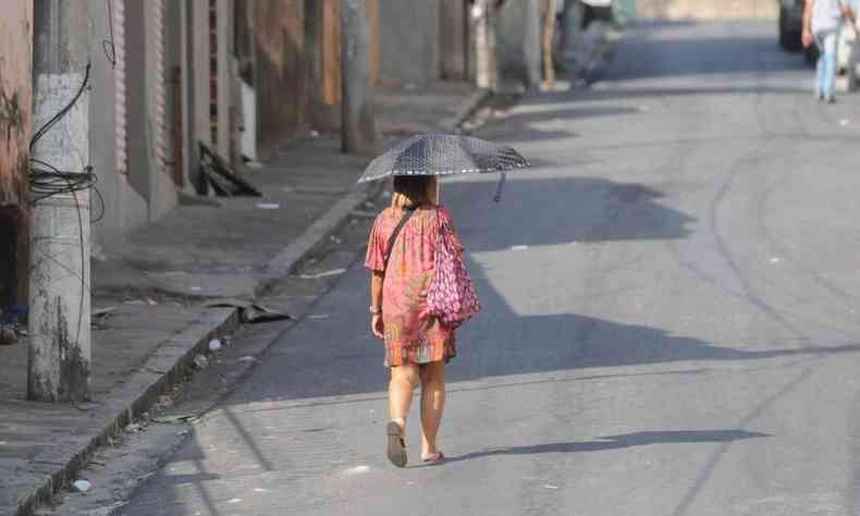 Mulher tentando se proteger do sol com guarda chuva