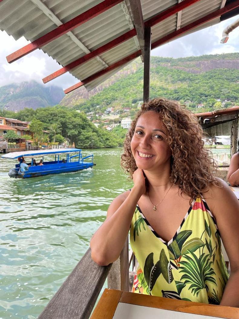 A consultora brasileira residente em Portugal Renata Lima. Ela est usando uma blusa amarela e sentada em uma varanda  beira de um rio