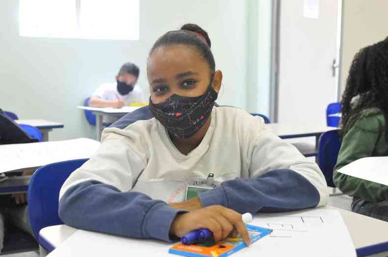 Estudante Maria Eduarda Cardoso sentada na carteira e usando máscara