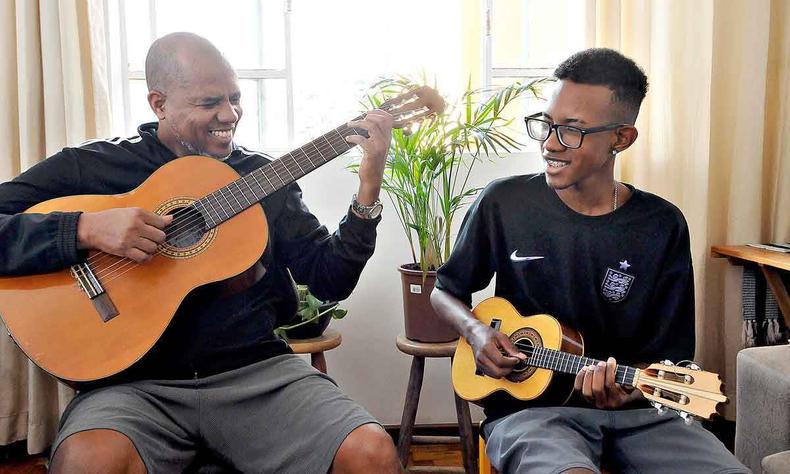 Sorrindo, D Lucas toca violo e o filho, o ator Ccero Lucas, toca cavaquinho 