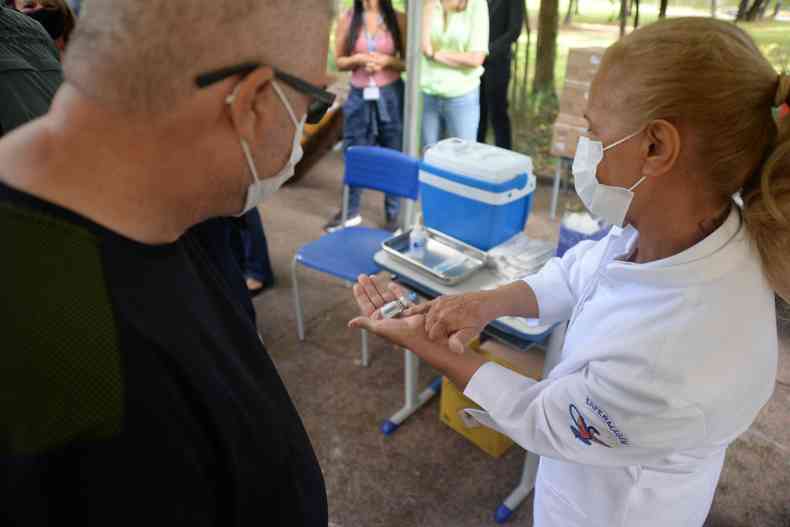 Enfermeira mostra rótulo de vacina para homem. 