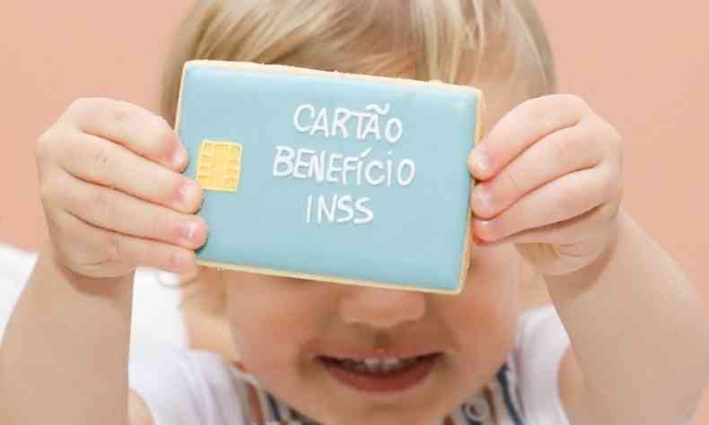 beb segurando biscoito axul escrito 'Carto Benefcio INSS'