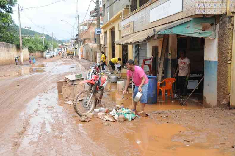 comerciantes limpando o comércio na rua cheia de lama