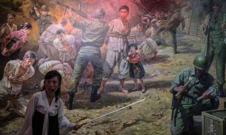 Guia mostra quadro que representa cena de soldados americanos se preparando para matar grupo de norte-coreanos(foto: Ed JONES / AFP)