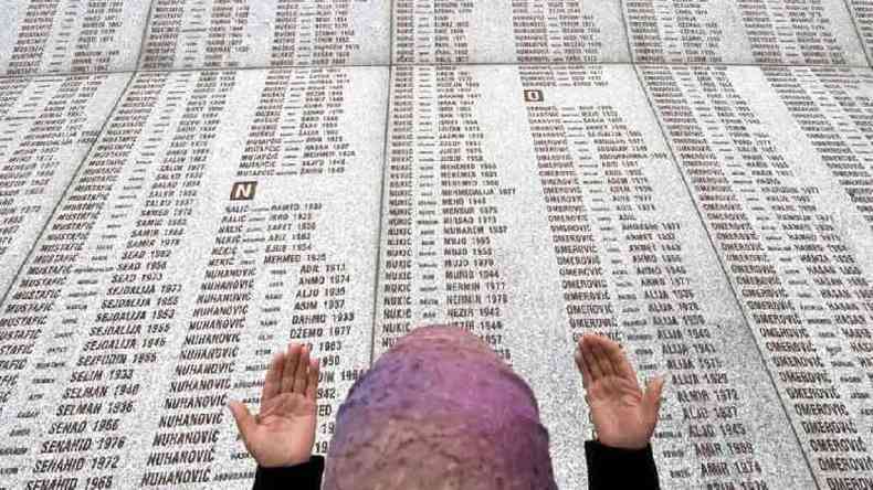 Mulher ora em frente a lista de mortos em genocdio na Srvia