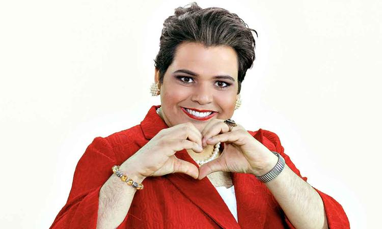 O humorista Gustavo Mendes imita Dilma Rousseff, fazendo gesto de corao com as mos e usando tailleur vermelho
