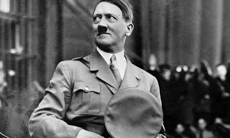 Adolf Hitler olha para o lado e segura o quepe