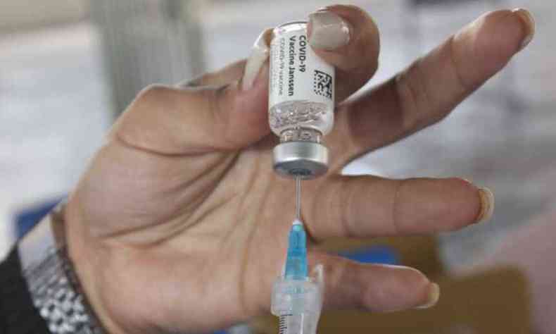 Enfermeira segura frasco com imunizante contra a COVID e agulha de injeção