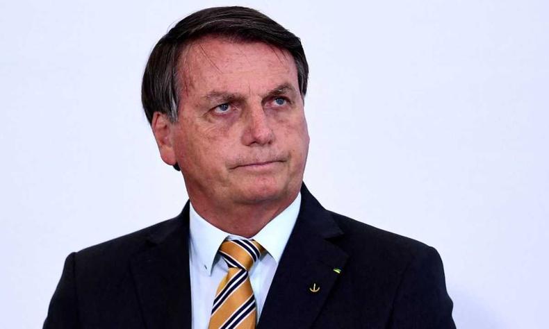 Jair Bolsonaro. Ele  um homem branco de cabelos castanhos mdio. Usa terno. Na imagem ele est com uma expresso facial de abalado