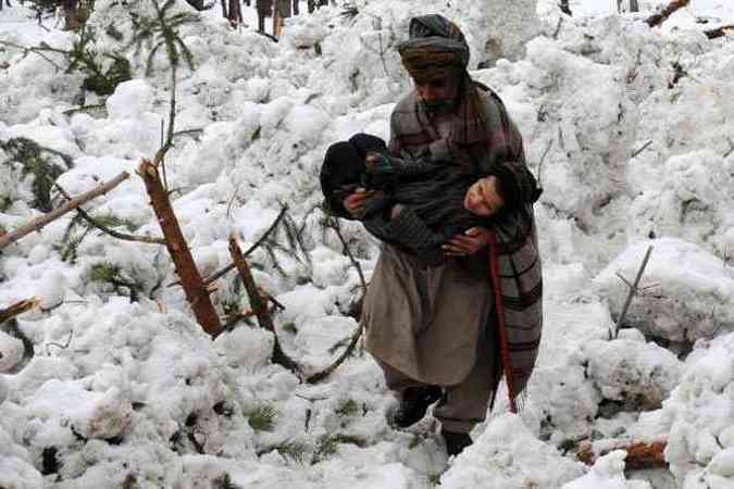 Morador socorre um parente que foi resgatado da neve na cidade de Ramwari, na ndia (foto: ROUF BHAT / AFP)