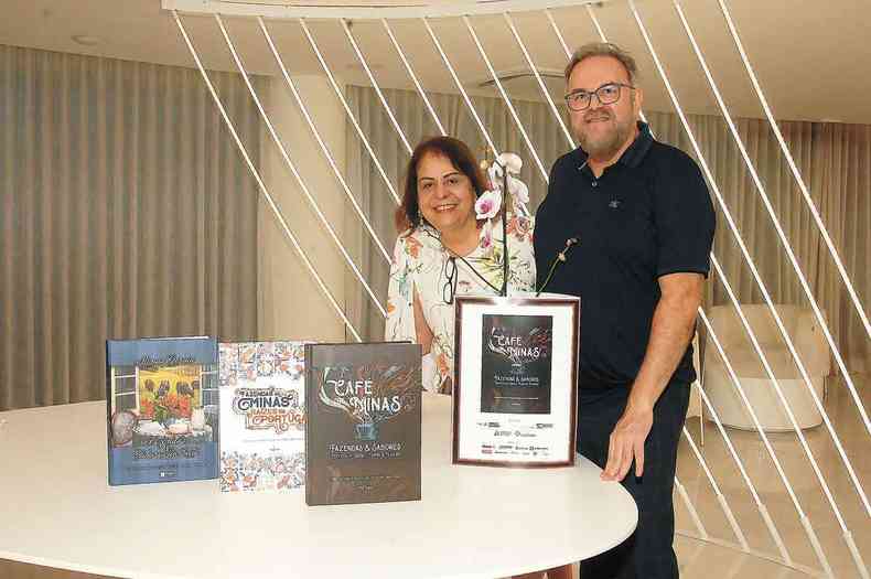 Patrcia Soutto Mayor e Clsio Barbosa em volta de mesa com capas de livros e orqudea 