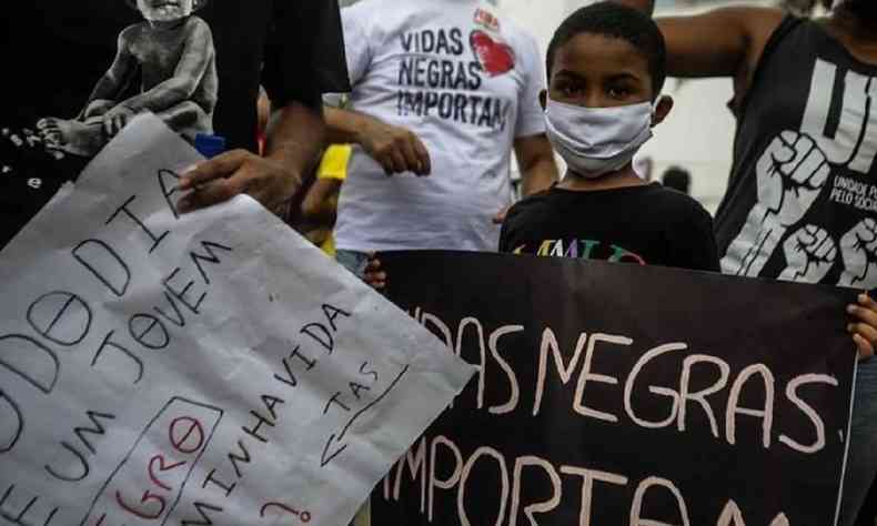 Criança segurando cartaz com a inscrição 'Vidas negras importam' em manifestação