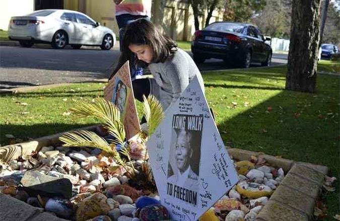 Uma crian�a coloca mensagens de apoio ao ex-presidente Nelson Mandela, em frente � casa dele em Joanesburgo, na �frica do Sul(foto: REUTERS/Mujahid Safodien)