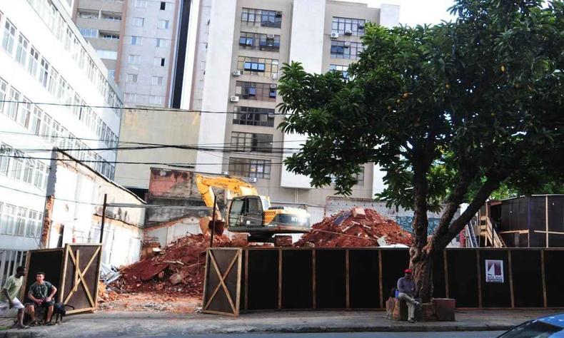 Um terreno em construo, com trator ao fundo e uma rvore no passeio