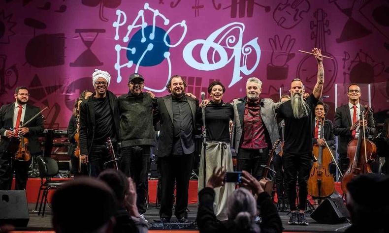 No palco, msicos da banda Pato Fu e o maestro Rodrigo Toffolo esto abraados e agradecem ao pblico. Ao fundo veem-se integrantes da Orquestra Ouro Preto