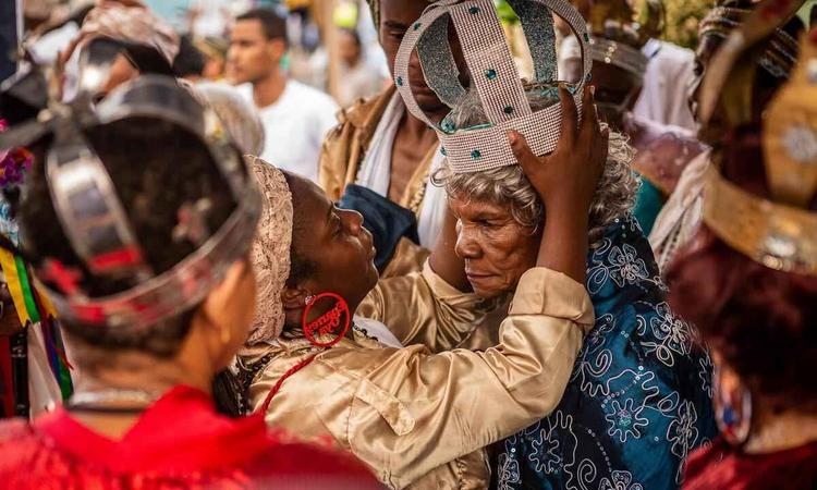 Mulher coloca a coroa em senhora em grupo de congado retratado pelo fotógrafo Patrick Arley