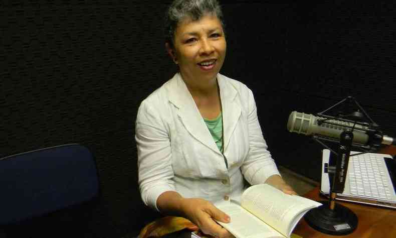 Professora paraguaia Graciela Chamorro est em frente a microfone, sorrindo para a cmera e folheando livro
