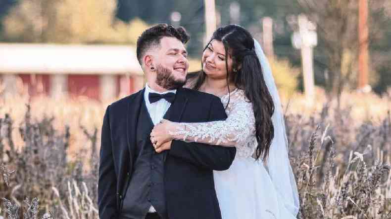 Um casal em trajes de casamento fotografados em um campo de flores