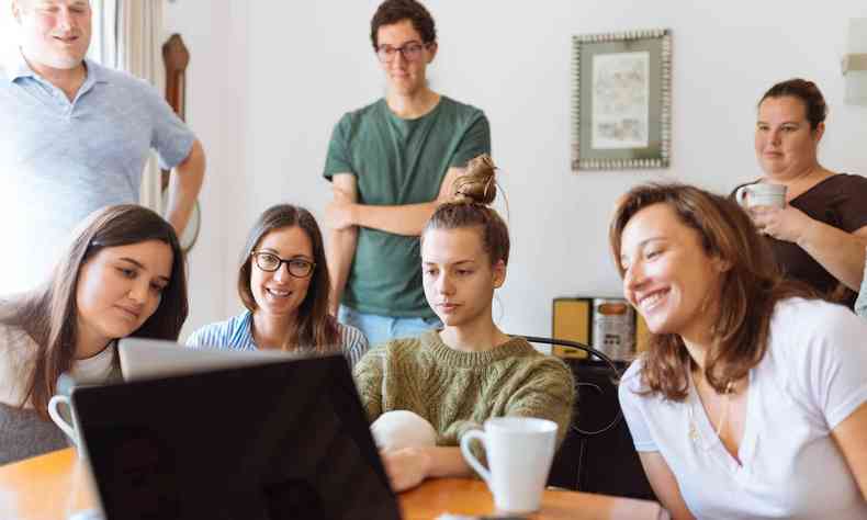 Grupo de pessoas reunido para ver algo no computador 