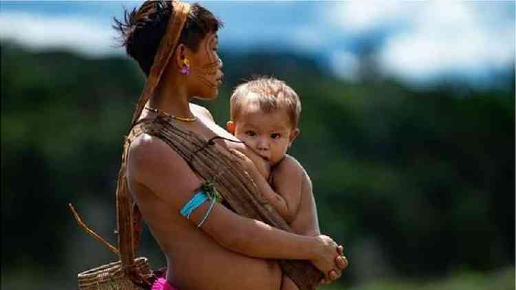 Mãe yanomami amamenta seu bebê enquanto espera em um posto de saúde no Brasil