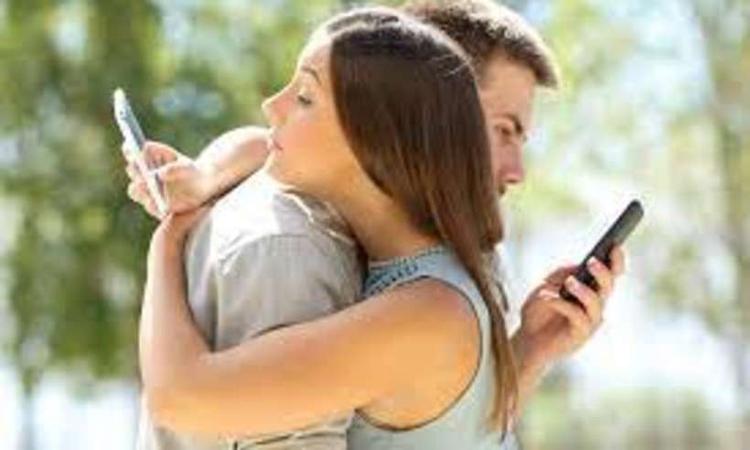 casal abraado e cada um de olho no seu smartphone