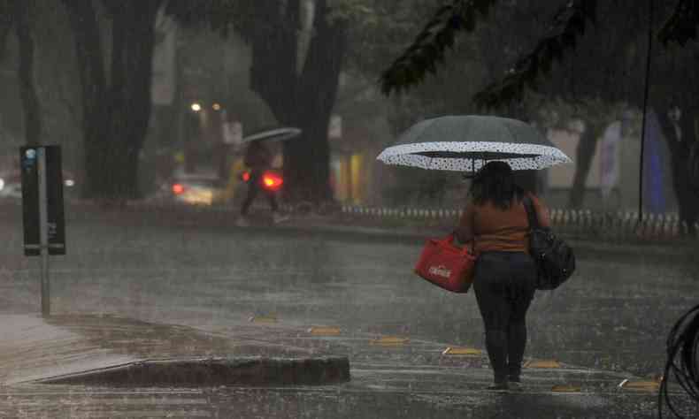 Chuva em Belo Horizonte. Mulher anda com guarda-chuva. 