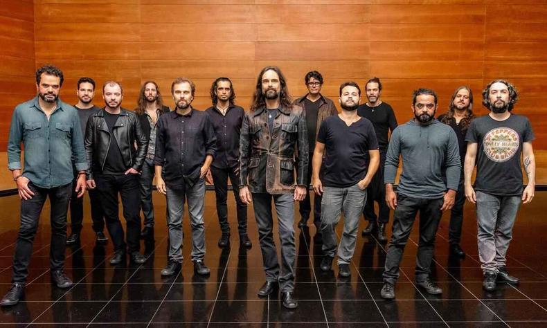 Os 13 msicos da Orquestra Mineira de Rock esto em p, lado a lado, e olham para a cmera