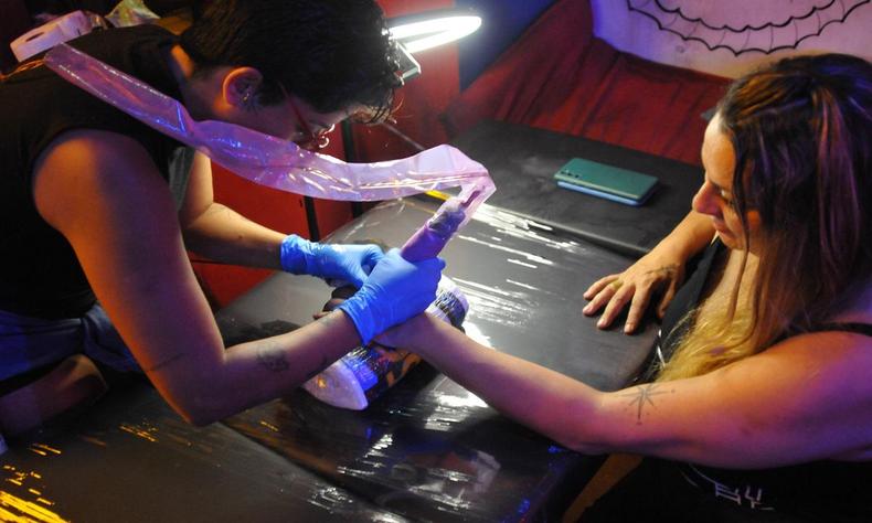 A tatuadora Thas fazendo uma flash tattoo