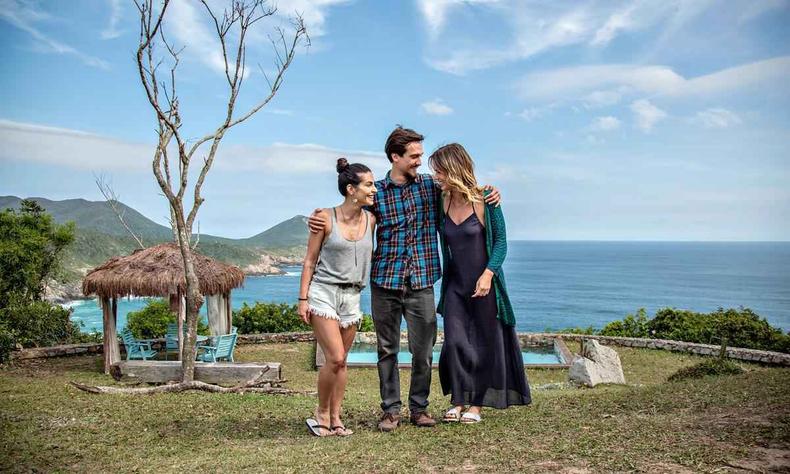 Dani (Cleo), André (Igor Angelkorte) e Beta (Juliana Didone) formam o 'triângulo família' de 'O amor dá voltas'(foto: Rachel Tanugi/divulgação) Atores Cleo, Igor Angelkorte e Juliana Didone estão abraçados em cenário praiano no filme O amor dá voltas