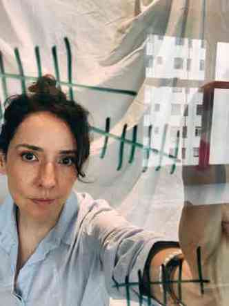 A escritora e jornalista Sabrina Abreu faz selfie em seu apartamento, tendo ao fundo o reflexo de um prdio na janela