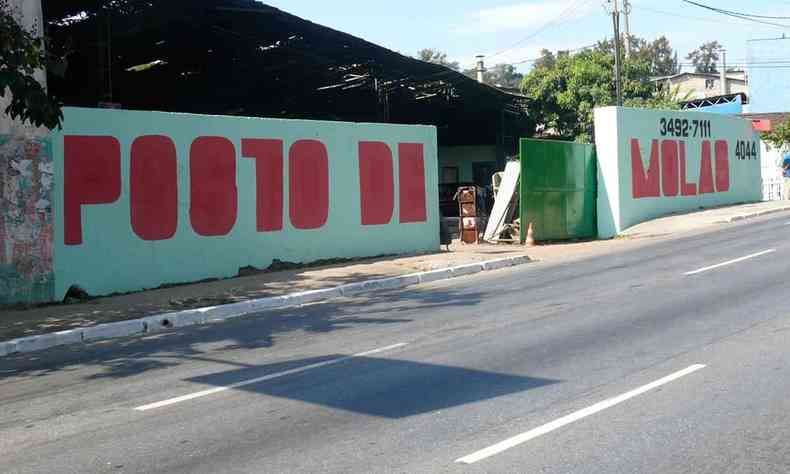 Muro com fundo verde-claro traz letras gigantescas escritas em vermelho, na obra Obliterado, de Marcelo Drummond