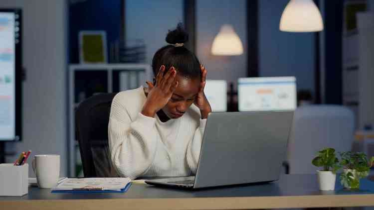 Mulher negra estressada no trabalho de frente para o computador