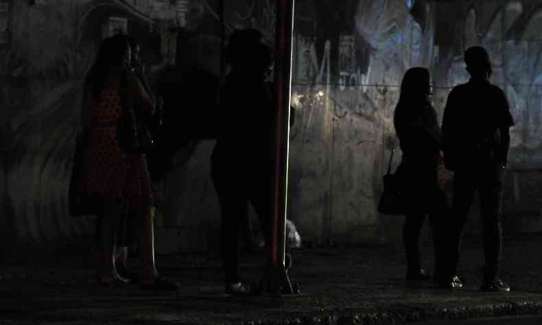 Pessoas aguardam ônibus em ponto de ônibus sem iluminação em Belo Horizonte