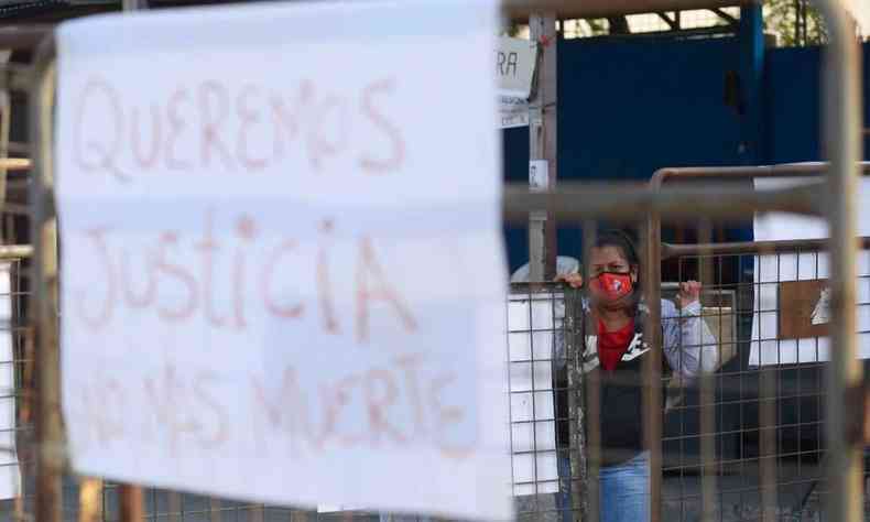 cartaz branco com letras vermelhas preso em grade pede Justia em frente a presdio do Equador onde 68 detentos morreram