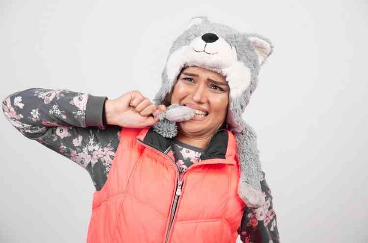 Mulher com roupa de frio com a mo na boca