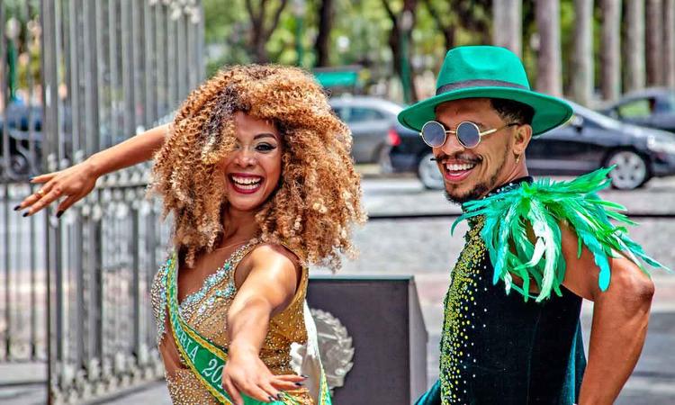 Aline Caldeira, rainha da Escola de Samba Canto da Alvorada, e rapaz no identificado, vestidos com trajes de carnaval, sorriem para a cmera