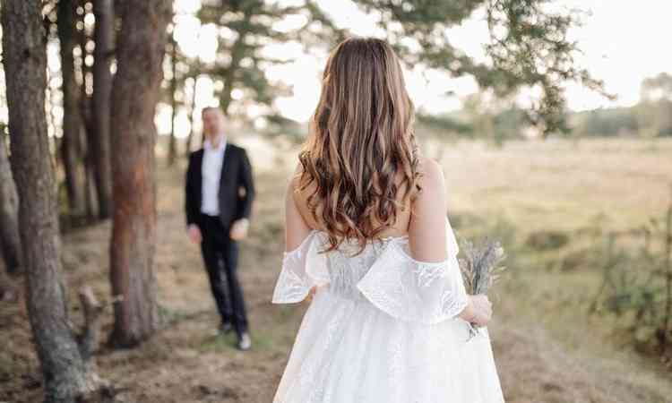 noiva de costas anda em direo ao noivo em um ambiente ao ar livre