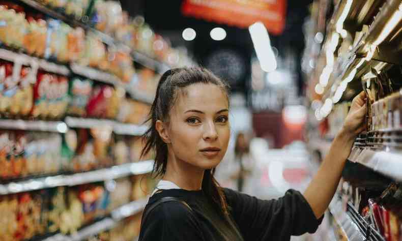 mulher em frente a prateleira de produto num supermercado