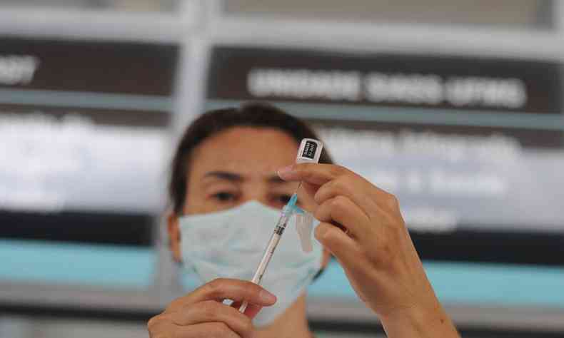 Profissional de sade prepara a seringa para aplicao da vacina 