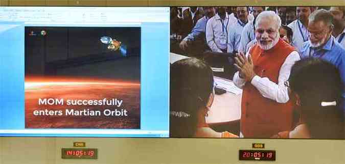 Primeiro ministro indiano Narendra Modi  visto em tela enquanto cumprimenta cientistas que trabalharam no bem-sucedido projeto de colocar a sonda na rbita de Marte (foto: AFP PHOTO/Manjunath KIRAN )