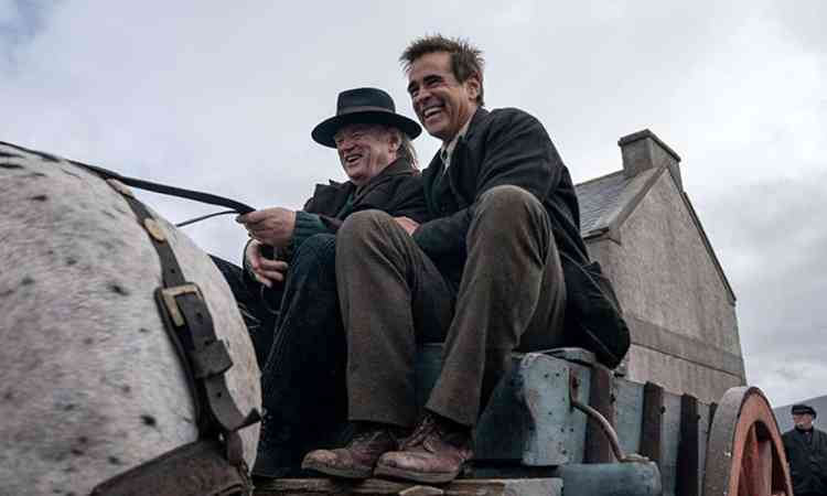 Atores Brendan Gleeson e Colin Farrell sorriem, sentados em carroa, no filme Os Banshees de Inisherin