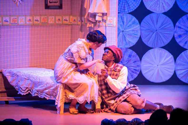 Ator que interpreta Milton Nascimento, sentado no cho, conversa com atriz sentada na cama, em quarto, em cena do musical