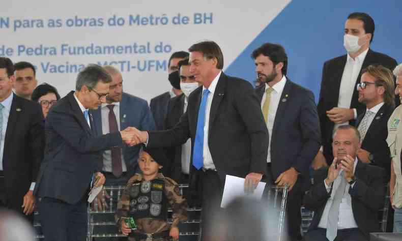 Bolsonaro e Zema do as mos e se cumprimentam durante evento sobre o metr de BH; no palco, esto, ainda, diversos polticos bolsonaristas