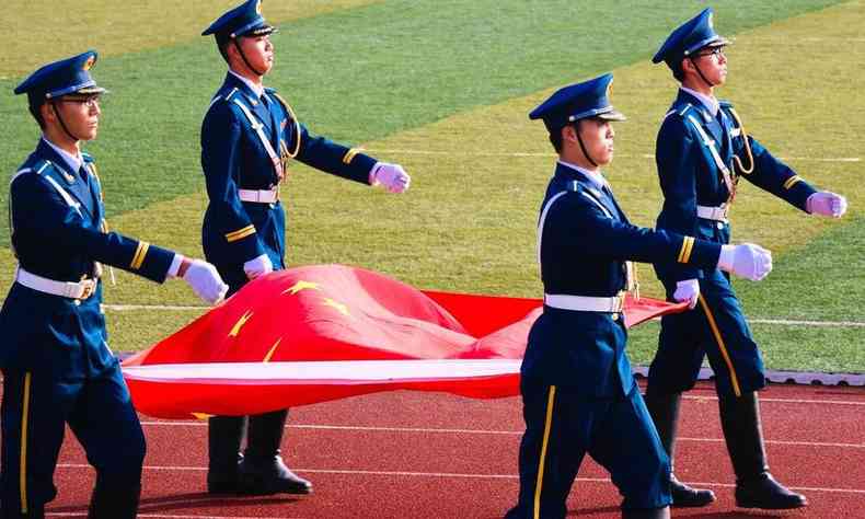 quatro soldados desfilam segurando a bandeira da China