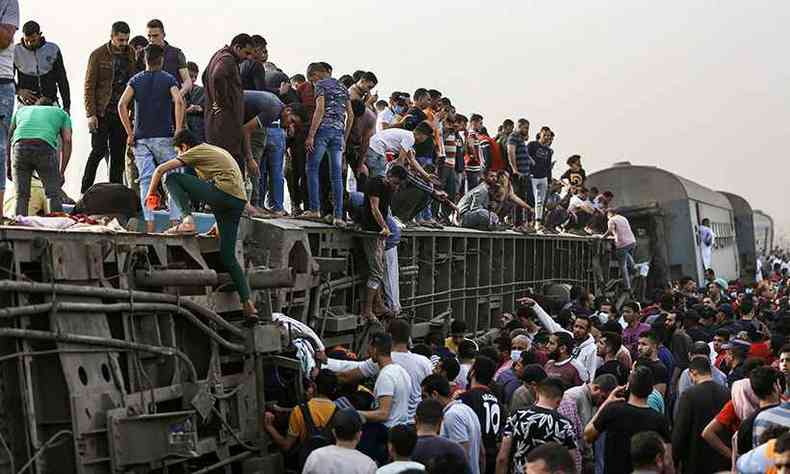 Pessoas sobem em vago tombado aps o acidente de trem (foto: Ayman Aref/AFP)
